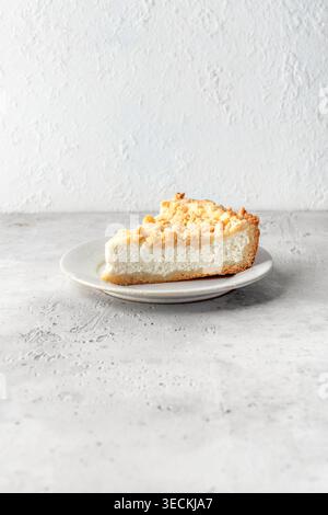 Scheibe hausgemachter Hüttenkäse Käsekuchen auf weißer Keramikplatte für Frühstück isoliert auf hellgrauem Tischhintergrund, Kopierraum. Vertikal Stockfoto