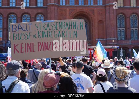 Berlin – 1. Mai 2026: Ein Demonstrant hält ein handgefertigtes Pappschild, das Sozialausgaben für militärische Investitionen im Roten Rathaus fordert. Stockfoto