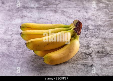 Ein paar frische gelbe Bananen mit einigen Reifen braunen Flecken auf einer rustikalen grauen strukturierten Oberfläche. Minimalistische Komposition mit natürlichem Licht, perfekt für h Stockfoto