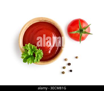 Blick von oben auf Ketchup, serviert in einer kleinen Schüssel, garniert mit frischer Petersilie und einer Kirschtomate. Die Szene wird auf einem weißen Hintergrund mit Ausschnitt isoliert Stockfoto