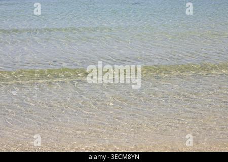 Klares, ruhiges Meereswasser, das sanft auf den Sandstrand plätschert, schafft eine ruhige und friedliche Atmosphäre, perfekt für Entspannung und Ruhe an warmen Sommertagen Stockfoto