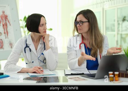 Zwei medizinische Fachkräfte führten während der Arbeitszeit in einem hellen medizinischen Büro eine ernsthafte Diskussion Stockfoto