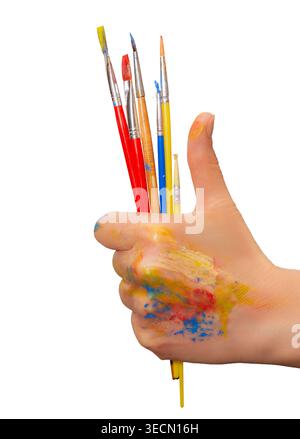 Eine Hand hält mehrere Pinsel und zeigt helle Farbflecken auf Fingern und Handflächen. Stockfoto