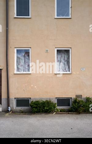 Einfache, schlichte Gebäudefassade mit zwei Fenstern und überdachten Vorhängen für Privatsphäre. Nynashamn, Stockholmer County, Schweden, 25. Mai 2025 Stockfoto
