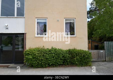 Einfache, schlichte Gebäudefassade mit zwei Fenstern und überdachten Vorhängen für Privatsphäre. Nynashamn, Stockholmer County, Schweden, 25. Mai 2025 Stockfoto
