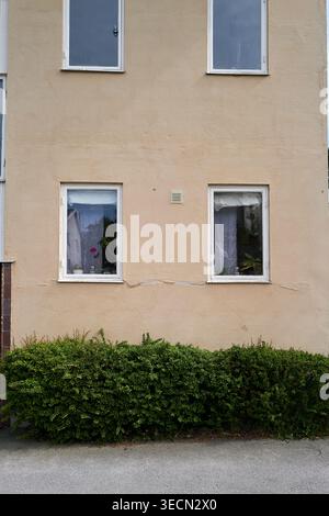 Einfache, schlichte Gebäudefassade mit zwei Fenstern und überdachten Vorhängen für Privatsphäre. Nynashamn, Stockholmer County, Schweden, 25. Mai 2025 Stockfoto