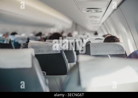 Passagiere, die während des Tagesflugs in der Economy-Kabine eines Geschäftsflugzeugs sitzen Stockfoto