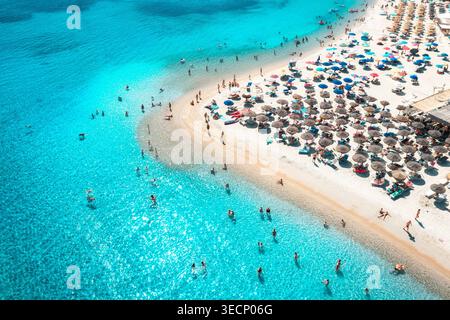 Blick aus der Vogelperspektive auf bunte Sonnenschirme am weißen Sandstrand, blaues Meer Stockfoto