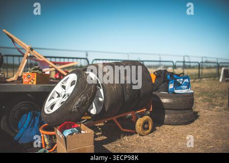 Ein Stapel Reifen sitzt auf einem Wagen, bereit für den Einsatz bei einem Rennen, mit einem klaren blauen Himmel über dem Wagen Stockfoto