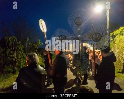 Gläubige, die ein großes, reich verziertes traditionelles Kreuz bei der dunklen Nachtwession am Karfreitag zum orthodoxen Ostern in einem Dorf in Korfu, Griechenland, tragen Stockfoto