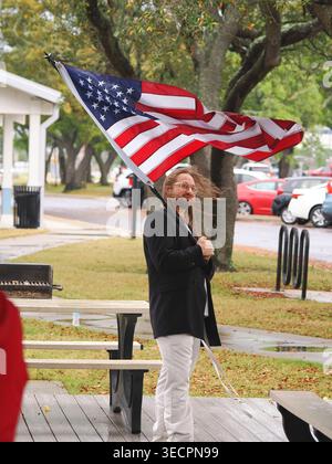 Panama City, FL, USA. Mai 2026. Ein Demonstrant hält im Carl Gray Park eine amerikanische Flagge, die vom Windböen gepeitscht wird, während die Strong-Rallye am Mai aufgrund von Regen und Wind verzögert startet. Der koordinierte nationale Aktionstag, der unter dem Banner der Arbeiter über Billionäre organisiert wurde, rief zu No Work, No School, No Shopping auf. Die Demonstranten planten, zur Hathaway Bridge zu gehen, um die Besteuerung der Reichen, ein Ende der EISATTACKEN und den Schutz des Wahlrechts zu fordern. Quelle: Tosh Persons / Alamy Live News Stockfoto
