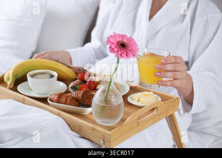Frau isst köstliches Frühstück im Bett drinnen, Nahaufnahme Stockfoto