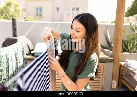 Erwachsene Frau hängt Wäsche an der Wäscheleine im Freien Stockfoto