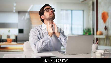 Ein Mann Mit Halsschmerzen Sitzt Auf Dem Laptop Und Sucht Fernversorgung Wegen Schmerzen. Stockfoto