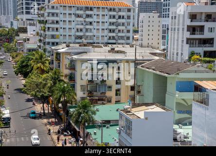 Erhöhter Blick auf ein dichtes Stadtviertel in Vietnam mit einer Mischung aus älteren flachen Apartmentgebäuden und modernen Hochhäusern. Ein Baum-l Stockfoto