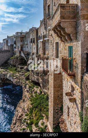 Die historischen weiß getünchten und steinernen Gebäude von Polignano a Mare, hoch oben auf steilen Klippen mit Blick auf das Meer unter einem warmen, bewölkten Himmel. Apulien Stockfoto