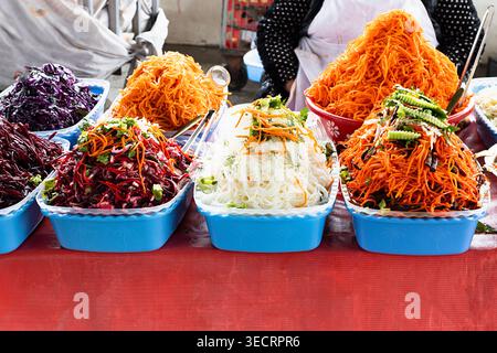 Bunte geriebene Gemüsesalate, hoch in blauen Tabletts auf dem Siab Basar in Samarkand. Lebendige Street Food-Displays, ideal für Reisen und kulinarische Highlights Stockfoto