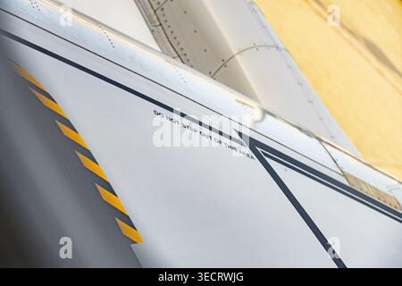 Nahaufnahme einer Flügelfläche für gewerbliche Flugzeuge mit diagonalen Sicherheitsstreifen und NICHT-TRITTWARNUNG, mit Nieten und Metallplatten im Kriegszustand Stockfoto