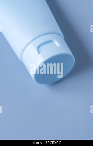 Nahaufnahme einer minimalen kosmetischen Creme-Tube mit Kappe auf pastellblauem Hintergrund. Reinigen Sie das Modell der Hautpflegeverpackung mit weichem Licht. Stockfoto