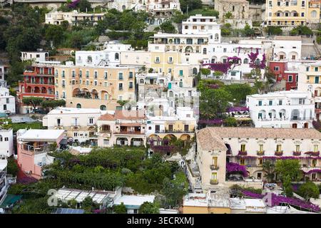 Panoramablick auf das Dorf am Hügel der Amalfiküste mit pastellfarbenen mediterranen Häusern, Terrassen und pulsierenden Bougainvillea über üppigem Grün im Süden Stockfoto