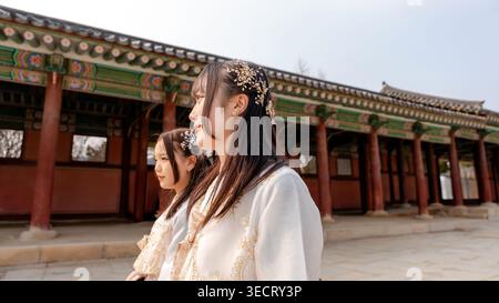 Zwei Frauen in traditionellen koreanischen Hanboks schlendern durch den historischen Gyeongbokgung Palace in Seoul, Südkorea, mit Vihrau Stockfoto