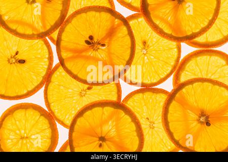 Nahaufnahme des Hintergrunds von überlappenden Zitrusfrüchtescheiben, leuchtendes Orange im Hintergrund, mit saftigen Segmenten und Schälenstruktur für frisches Essen. Stockfoto