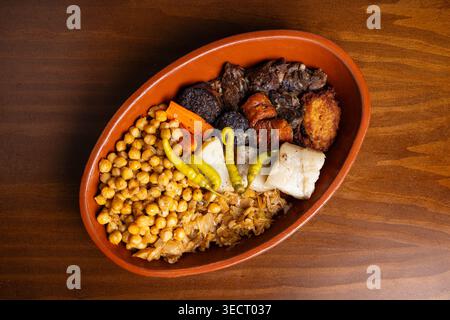 Eine köstliche Auswahl an traditionellem spanischen Cocido mit Kichererbsen, Fleisch und Gemüse in einer rustikalen Schüssel. Perfekt für die Präsentation von klassischem Spanisch Stockfoto