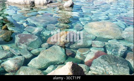 Steine im klaren Wasser. Kieselsteine unter Wasser. Die Aussicht von oben. Texturen Hintergrund. Sauberes Flusswasser. Transparenter Fluss Stockfoto