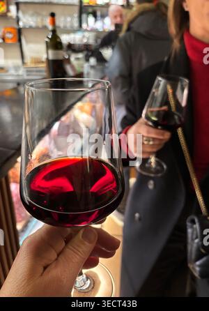Nahaufnahme einer Hand mit einem Glas Pinot Noir Rotwein während einer Verkostung in einer eleganten Weinbar am Abend. Stockfoto