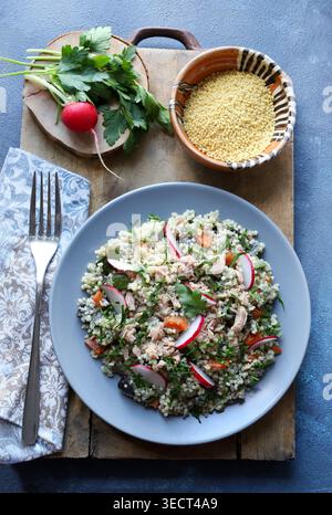 Gesunder mediterraner Couscous-Salat mit Thunfisch, frischem Rettich und Petersilie auf einem rustikalen Holzbrett. Couscous Tabbouleh. Mediterranes Ernährungskonzept. Stockfoto