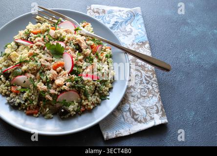 Gesunder mediterraner Couscous-Salat mit Thunfisch, frischem Rettich und Petersilie auf blauem Hintergrund. Couscous Tabbouleh. Mediterranes Ernährungskonzept. Stockfoto