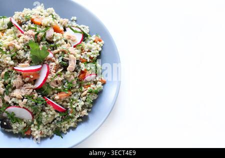 Gesunder mediterraner Couscous-Salat mit Thunfisch, frischem Rettich und Petersilie auf weißem Hintergrund. Couscous Tabbouleh. Mediterranes Ernährungskonzept. Stockfoto