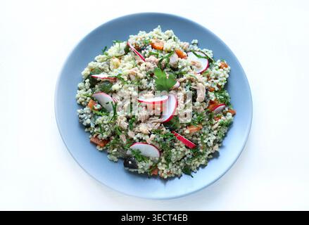 Gesunder mediterraner Couscous-Salat mit Thunfisch, frischem Rettich und Petersilie auf weißem Hintergrund. Couscous Tabbouleh. Mediterranes Ernährungskonzept. Stockfoto