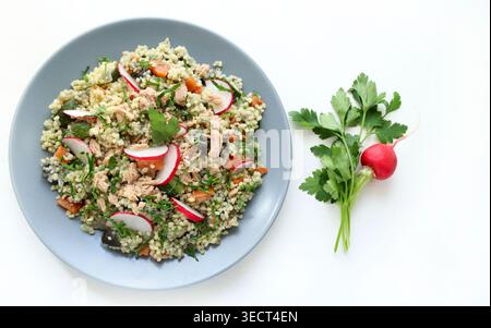 Gesunder mediterraner Couscous-Salat mit Thunfisch, frischem Rettich und Petersilie auf weißem Hintergrund. Couscous Tabbouleh. Mediterranes Ernährungskonzept. Stockfoto