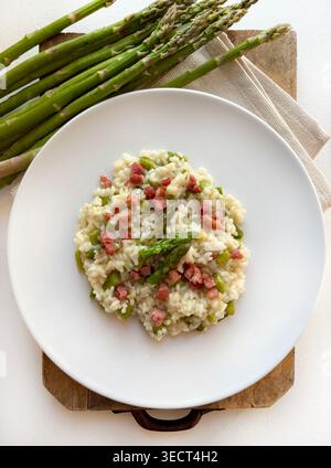 Nahaufnahme eines Gourmet-Spargels und knusprigem Speckrisotto, serviert auf einem modernen Teller. Helle, luftige Lebensmittelfotografie mit Frühlingsmotiven. Draufsicht. Stockfoto