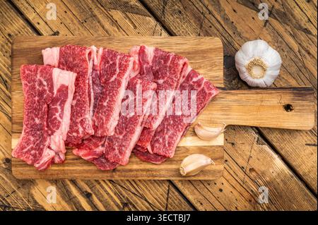 Luxuriöses marmoriertes Rindfleisch, kurze Tellerscheiben, die Wagyu-Textur auf Holzbrett mit Kräutern ähneln, rohes angus-Fleisch-Zubereitungskonzept Stockfoto
