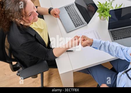 Draufsicht auf zwei Kollegen, die den Konferenztisch mit der Faust überspringen, Vielfalt im Büro gefeiert. Stockfoto