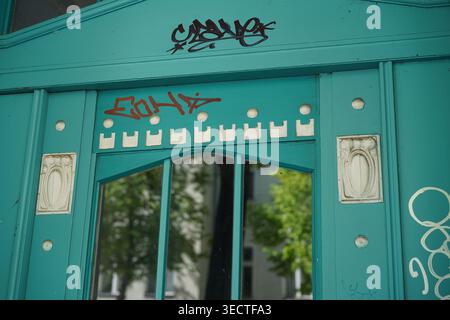 Berlin - 2. Mai 2026: Detail einer türkisfarbenen Jugendstilholztür mit geometrischen Ornamenten und Graffiti-Tags in der Karl-Kunger-Straße. Stockfoto