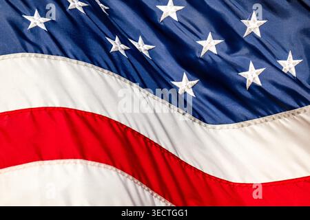 Vereinigte Staaten Flagge Gestickte Sterne wehen in Washington DC Vereinigte Staaten | WASHINGTON D.C., Vereinigte Staaten — Eine Nahaufnahme zeigt die gestickten weißen Sterne und genähten Streifen einer US-Flagge, die im Wind wehen. Das aktuelle 50-Sterne-Design wurde von Robert G. Heft entworfen und 1960 übernommen, nachdem Hawaii der Union beigetreten war. Bundesspezifikationen, die durch Executive Order 10834 festgelegt wurden, regeln die genauen Proportionen und offiziellen Farben, die als Old Glory Red und Old Glory Blue bekannt sind. Stockfoto