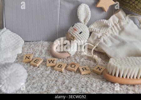 Neugeborene mit hölzernen Buchstabenfliesen, umgeben von natürlichen Babypflegeprodukten Stockfoto