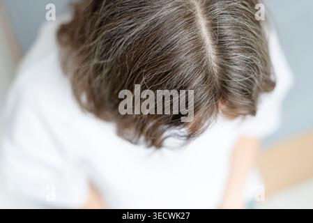 Nahaufnahme einer Frau, die friedlich ihr graues Haar mit einem sanften Lächeln annahm. Der reife Erwachsene hat sich mit natürlichen Alterungszeichen vollkommen beruhigt. Mutter umarmt ihre Silberstränge mit Liebe. Stockfoto