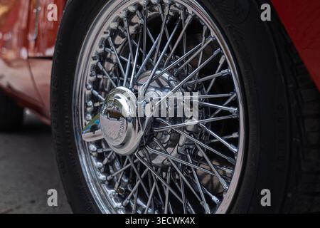 Nahaufnahme eines klassischen verchromten Speichenrads mit abbrechbarer Nabe des roten Triumph GT6 Sportwagens Stockfoto