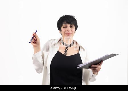 Reife Frau, die ein Klemmbrett hält und einen Stift hält, der es ansieht Stockfoto