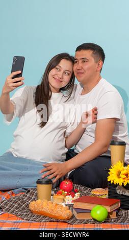 Glückliches Paar, das während des Picknicks Fotos mit einem Telefon macht Stockfoto