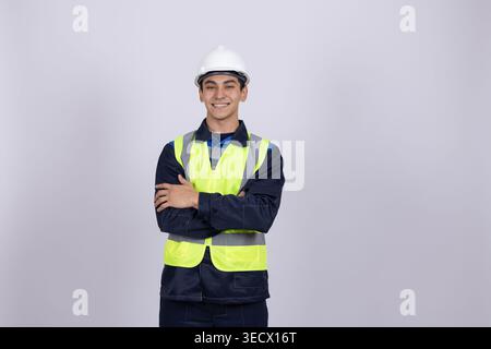 Junge Arbeiter in Sicherheitsweste und Helm mit gekreuzten Armen Stockfoto