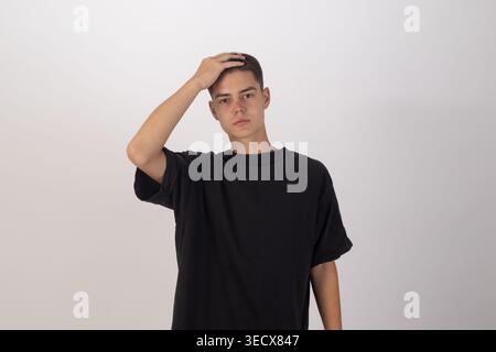 Junger Mann in schwarzem T-Shirt, der seine Stirn berührt Stockfoto
