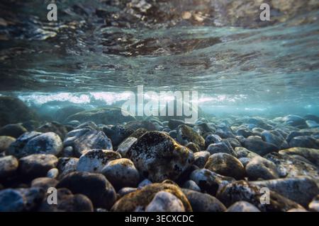 Unterwassermeer mit Steinen Meeresboden, Sonnenstrahlen im blauen Wasser. Stockfoto