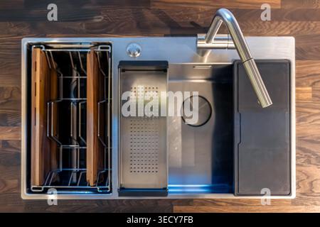 Modernes Küchenwaschbecken auf hölzerner Arbeitsfläche. Draufsicht des funktionalen Arbeitsbereichs mit Wasserhahn. Stockfoto