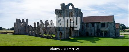 Panoramablick auf die Ruinen der Castle Acre Priory Kirche und Klostergebäude auf einem grünen Rasen unter blauem Himmel, Castle Acre, Norfolk, England, Vereinigtes Königreich Stockfoto