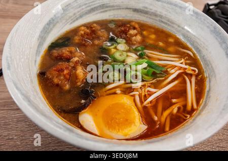 Eine dampfende Schüssel authentischer japanischer Ramen mit knusprigem gebratenem Huhn, frischen Bohnensprossen, Schnittlauch und einem weichgekochten Ei mit Marmelade Stockfoto